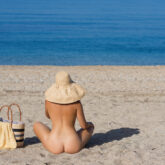 Beautiful female in the bikini and straw hat on the beach and sea background